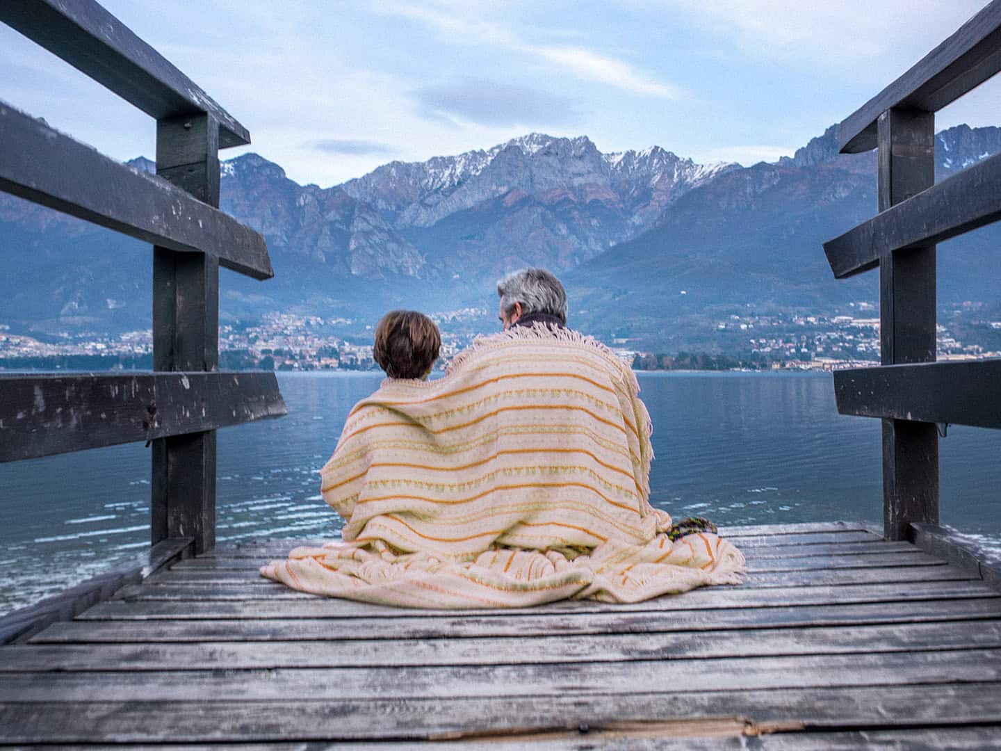 A father and child sitting together on a wooden pier looking out over a calm lake towards distant mountain horizons, representing legacy, family protection, and long-term financial planning with N2 Asset Management.